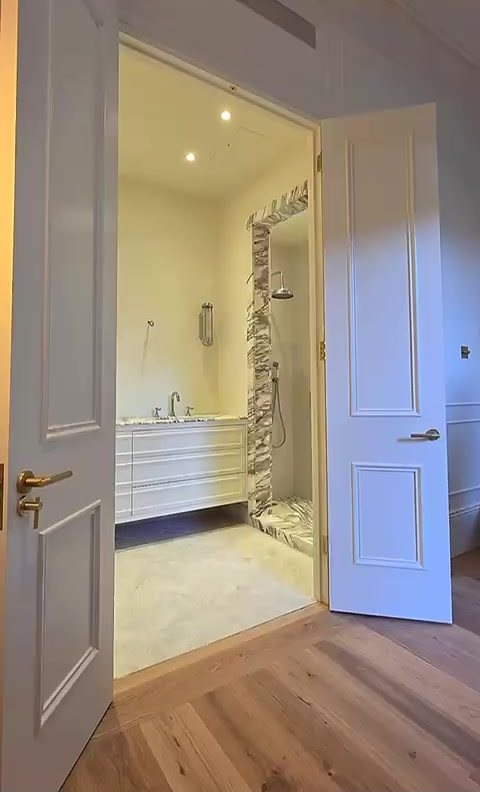 Finished marble bathroom through panelled doors